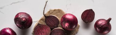 panoramic shot of red onions and beetroots on marble table with hessian clipart