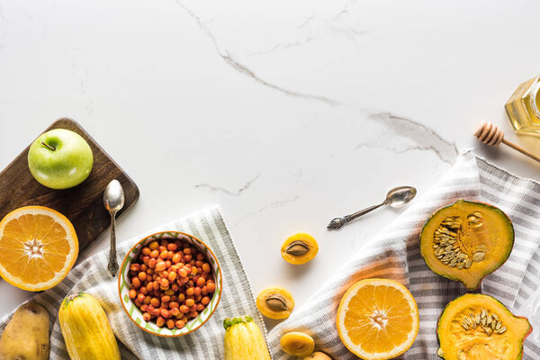 top view of striped towel fruits and vegetables near bowl with sea buckthorn on marble surface