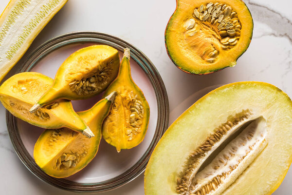 top view of plate with pumpkin parts and melon on marble surface