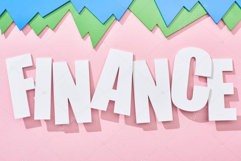 top view of finance inscription with green and blue statistic graphs on pink background