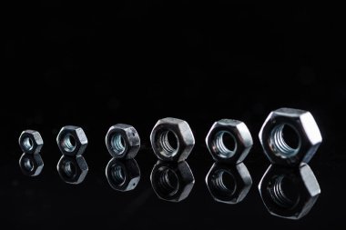 row of metallic nuts isolated on black clipart