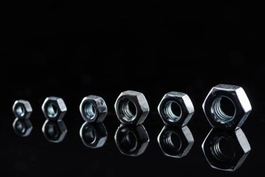 metal nuts of different sizes isolated on black clipart