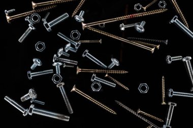 top view of scattered various screws isolated on black clipart