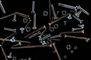top view of scattered bolts, nuts and studs isolated on black clipart