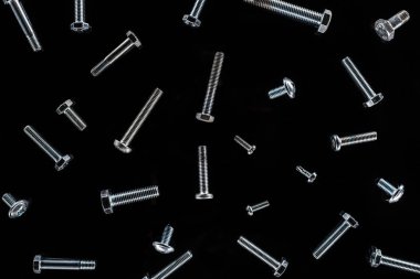 top view of scattered metal bolts pattern isolated on black clipart