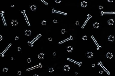 top view of scattered metal nuts and bolts pattern isolated on black clipart