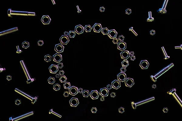 黒で隔離された散乱金属ナットとボルトの円の上図 — ストック写真