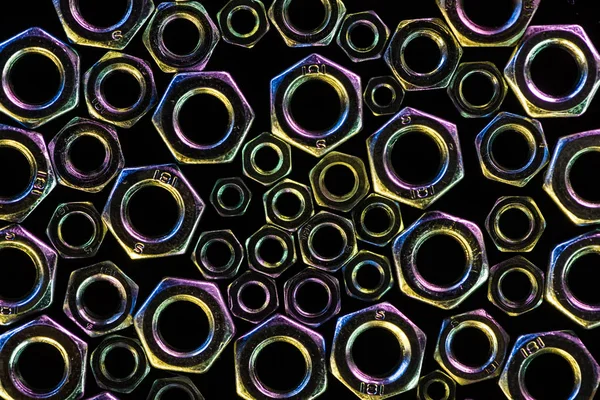 隔离在黑色上的分散的多种金属螺母的特写视图 — 图库照片