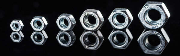 panoramic shot of shiny new metallic nuts isolated on black