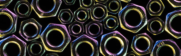 panoramic shot of scattered small and big metal nuts isolated on black