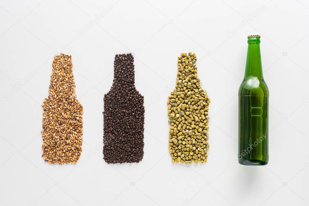 top view of bottle of beer near wheat, coffee grains and pressed hop isolated on white
