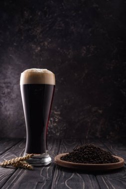 ahşap masa üzerinde kahve taneleri ile buğday sivri ve plaka yakın koyu bira cam