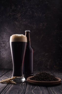 ahşap masa üzerinde kahve taneleri ile buğday sivri ve plaka yakın şişe ve bira cam