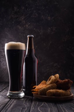 ahşap masada aperatifler ile plaka yakınında şişe ve bira cam