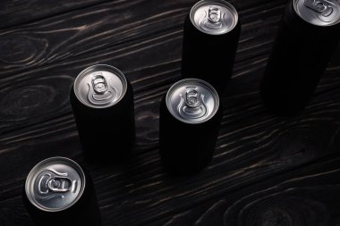 black metallic cans of beer on wooden table  clipart