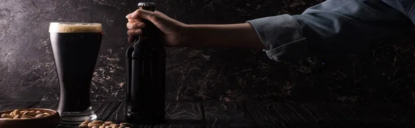 Przycięte Widok Człowieka Trzymając Butelkę Pobliżu Szklanki Ciemnego Piwa Miski — Zdjęcie stockowe