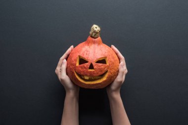 siyah arka plan üzerinde ürkütücü Halloween kabak tutan kadın kısmi görünümü
