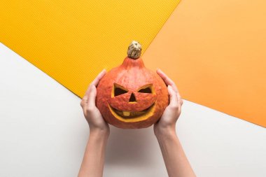 beyaz ve turuncu arka plan üzerinde Halloween balkabağı tutan kadın kırpılmış görünümü