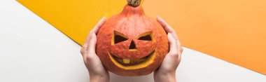 beyaz ve turuncu arka plan üzerinde Halloween balkabağı tutan kadın kırpılmış görünümü