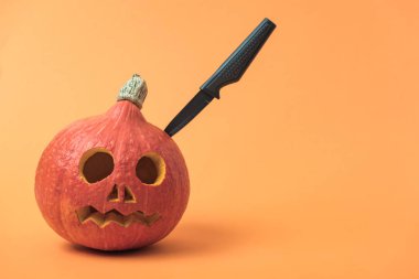 Turuncu arka plan üzerinde bıçak ile Halloween kabak