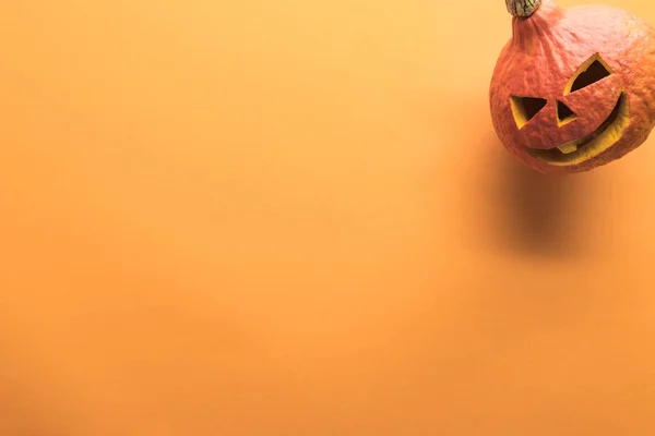 オレンジ色の背景に刻まれたハロウィーンカボチャのトップビュー — ストック写真