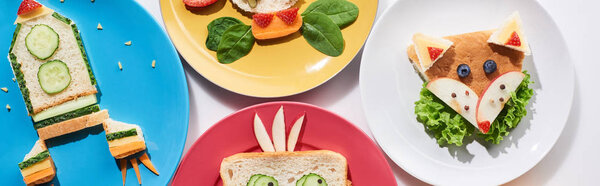 вид сверху на тарелки с модными животными и ракетой, изготовленные из продуктов питания для детей завтрак на белом фоне, панорамный снимок
