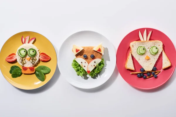 stock image top view of plates with fancy cow, bird and fox made of food for childrens breakfast on white background