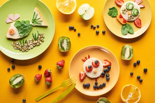 在五颜六色的橙色背景上用食物制成的花哨动物的盘子的顶视图 — 图库照片