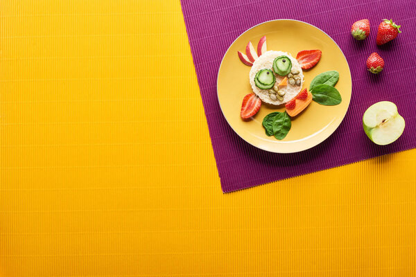 top view of plate with fancy cow made of food on purple and orange background