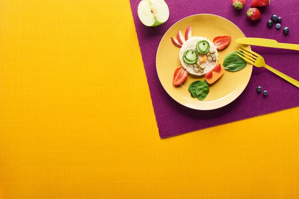 紫とオレンジの背景にカトラリーと食品で作られた派手な牛とプレートのトップビュー — ストック写真