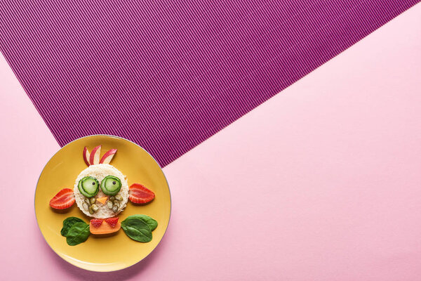 top view of plate with fancy cow made of food on pink and purple background