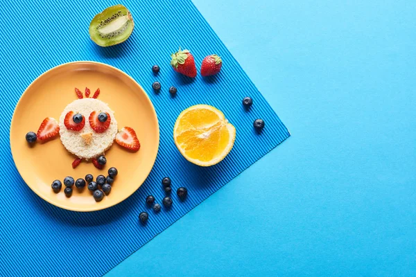 青い背景に食べ物で作られた派手な動物とプレートのトップビュー — ストック写真