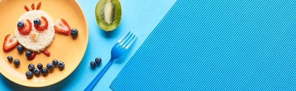 青い背景に食べ物で作られた派手な動物とプレートのトップビュー パノラマショット — ストック写真
