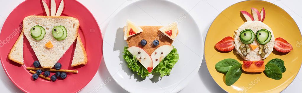 top view of plates with fancy cow, bird and fox made of food for childrens breakfast on white background, panoramic shot