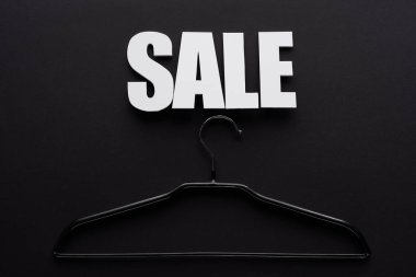 top view of white sale lettering with hanger on black background clipart