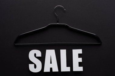 top view of white sale lettering with hanger on black background clipart