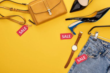 top view of fashionable clothing and accessories with sale labels on yellow background clipart