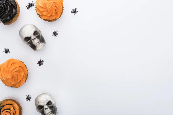 コピースペースと白い背景にクモや頭蓋骨とおいしいハロウィーンカップケーキのトップビュー — ストック写真