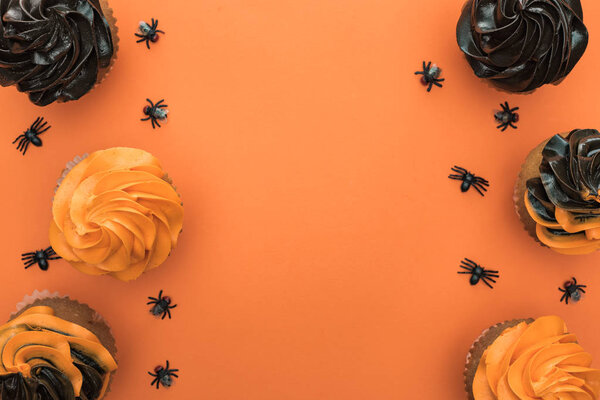 прекрасный вид на вкусные кексы Хэллоуин с пауками на оранжевом фоне с копировальным пространством
