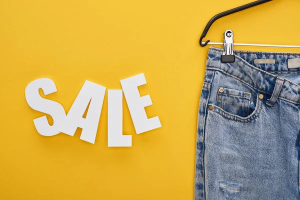Top View Jeans Hanger Sale Lettering Yellow Background — Stock Photo, Image