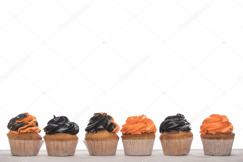 row of delicious Halloween orange and black cupcakes isolated on white