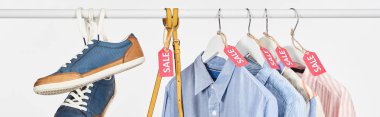 sneakers, bag and elegant shirts hanging with sale labels isolated on white, panoramic shot