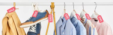sneakers, accessories and elegant shirts hanging with sale labels isolated on white, panoramic shot clipart