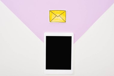 mor ve beyaz arka plan üzerinde boş ekran ve kağıt kesme mesaj simgesi ile dijital tablet üst görünümü