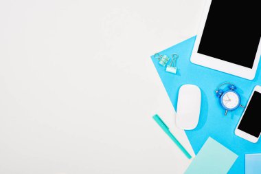 akıllı telefon üst görünümü, boş ekran lı dijital tablet ve mavi ve beyaz arka planda ofis malzemeleri ile bilgisayar faresi