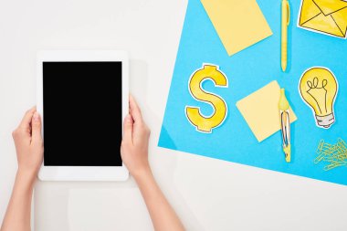 ofis malzemeleri ile işyerinde dijital tablet tutan kadın kırpılmış görünümü, mavi ve beyaz arka plan üzerinde sarı kağıt simgeleri