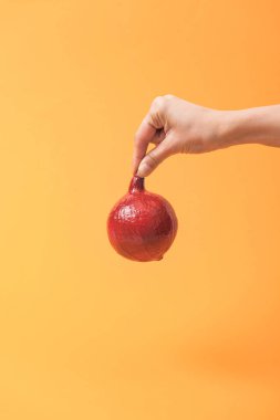 turuncu renkli arka plan üzerinde kırmızı boyalı kabak tutan kadın kısmi görünümü