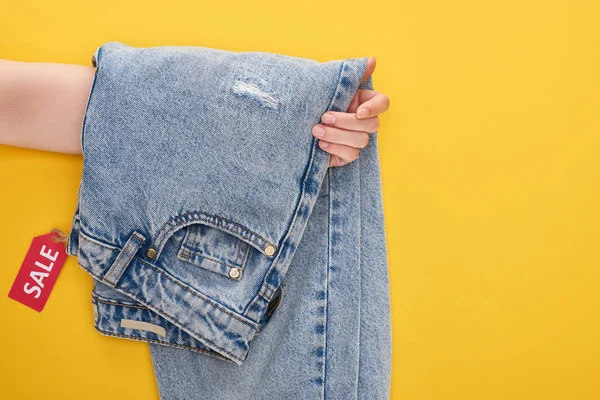 Beskärd Bild Kvinna Innehav Jeans Med Försäljning Etikett Gul Bakgrund — Stockfoto