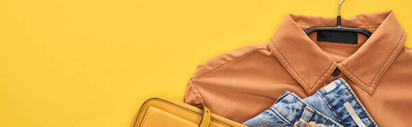 top view of bag, shirt and jeans isolated on yellow
