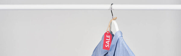 blue shirt hanging with sale label isolated on white, panoramic shot